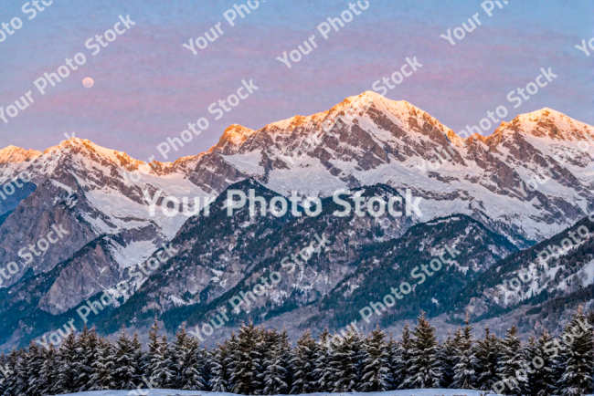 Stock Photo of Snowy mountains at sunset at altitude with forest